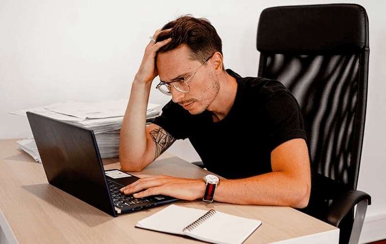 Hombre enfrente del ordenador expresando un sentimiento de estrés.